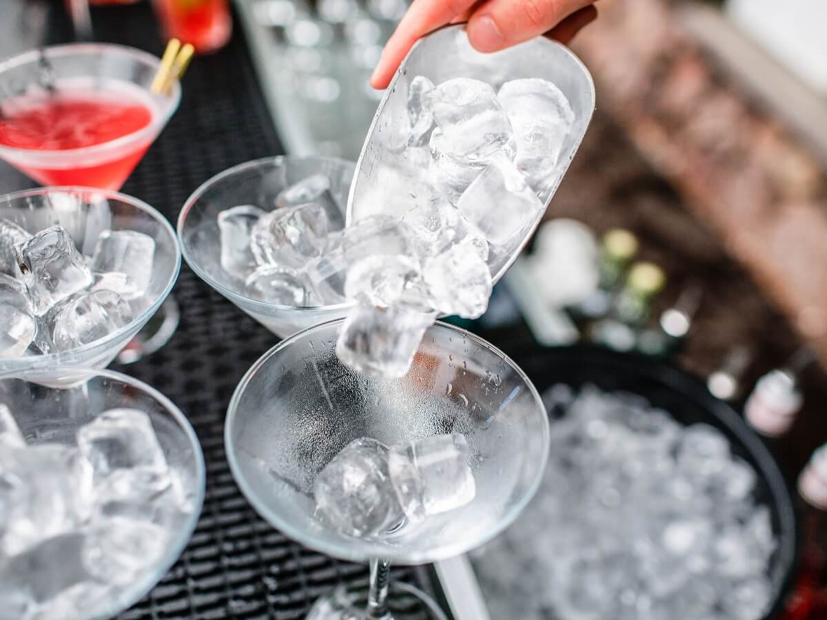 Servírovanie ľadových kociek do kokteilových pohárov.